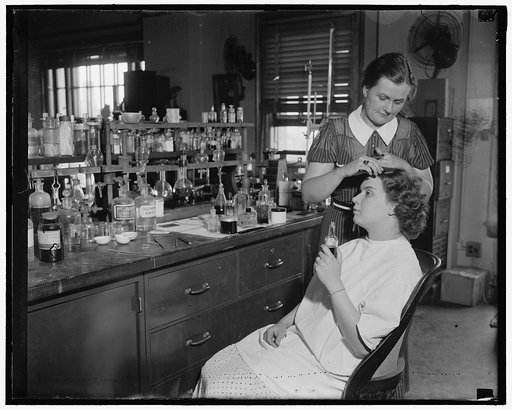 Testing cosmetics for the government. Washington D.C. July 10- Mrs. R. Goodman, is shown sitting with Mrs. C.R. West applying dye for the hair, some dyes contain lead and the poison in the dye may lead to chronic poisoning, the Department of Agriculture is continually on the lookout for false labels