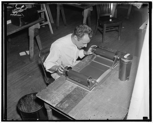 Inspects film for $3,000,000 map. Photographs for the map are made on a huge roll of film by the aerial cameramen. C.E. Kowaloczyk, AAA worker, is shown inspecting the film for flaws before it is sent in the laboratory to be printed, 7/28/37