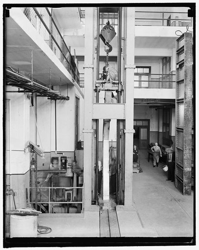 Bending huge steel girders. Washington, D.C., Sept. 23. At the U.S. Bureau of Standards officials were witnessing the testing of rigid steel frame knees that are used in grade eliminations such as over-passes, under-passes, bridges, etc. This photo shows the girder or knee placed into the huge 600,0