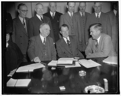 In spotlight at unemployment census conference at White House. Washington, D.C., Sept. 27. Secretary of Commerce Roper, (left) and Secretary of Agriculture Wallace, (right) go into a huddle with John D. Biggers, Unemployment Census Administrator, prior to the opening of the conference at the White H