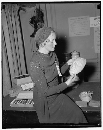 Death masks displayed at identification convention. Sept. 29. Mrs. Clark Schilder, wife of the Chief of the Division of Identification, Federal Bureau of Investigation, inspects a death mask of a trapped criminal at the Annual Convention of the International Association Identification which opened h