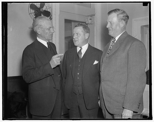 In spotlight at show hearing before tariff commission. Washington, D.C., Oct. 26. Charles F. Johnson, (right) first President of the Endicott- Johnson Corp., today told the Reciprocity Committee at the Tariff Commission that the Roosevelt Administration was being inconsistent in urging higher wages 