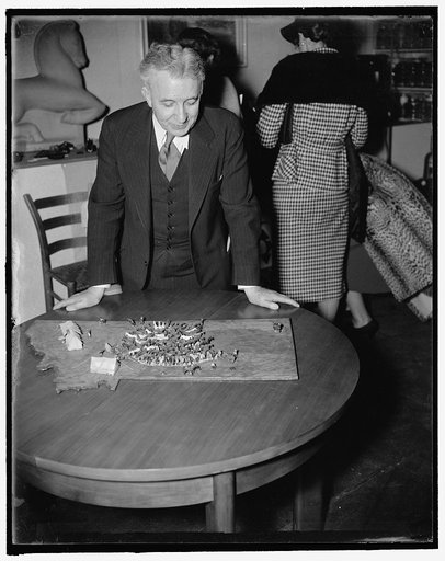 Allen Eaton, in charge of the exhibit. He is with the Russell Sage Foundation of New York City. Looking at the "Roundup" whittle by Hugh Haskins, of Montana. The board carved in shape of the state of Montana, holds 126 horses, chuck wagon, mess tent, pup tent and other things necessary for use durin
