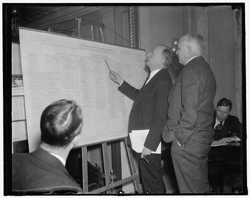 Rail Inquiry Chairman and Pennsy head view chart of Penna. R.R. holding companies. Washington, D.C., Dec. 15. A huge chart showing the numerous subsidiaries controlled by the Pennsylvania Railroad was on display at the Senate Rail Inquiry Committee room today. Chairman of the committee, Senator Burt