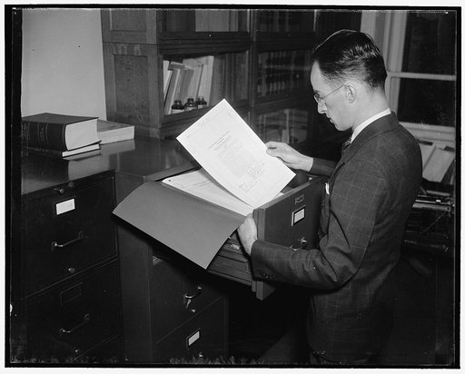 How a bill become a law. Now a law, the former bill, reprinted in legal form, is incorporated in the statutes-at-large and filed in the State Department. E.D. Kuppinger, Assistant Chief of the Law Section of the Division of Research and Republication of the State Department is showing placing a law 
