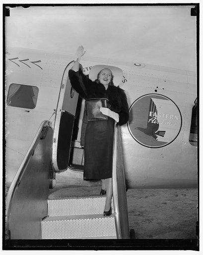 Apple blossom queen arrives. Washington, D.C., April 21. Adelaide Moffett Brooks, daughter of the former Federal Housing Administrator, and, who is to be crowned Queen Shenandoah at the Winchester, VA, Apple Blossom Festival later this month, waves a greeting as she arrives at Washington Airport. Wh