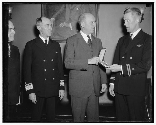 Rewarded for courage. Washington, D.C., May 12. Lieut. C.B. Olson (right) United States Coast Guard, receiving from Secretary of the Treasury Morgenthau today the distinguished Flying Cross, The first to be awarded to a Coast Guard Aviator. Lieut. Olson was awarded the cross in recognition of a flig