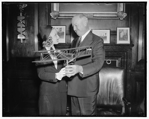 PMG Farley receives airmail plane model. Washington, D.C., May 18. Postmaster General James A. Farley, receives from Miss Marion Weldon, Paramount Starlet who is playing in the Paramount production "Men with Wings" a model of the De Haviland Liberty plane used twenty years ago for carrying airmail, 