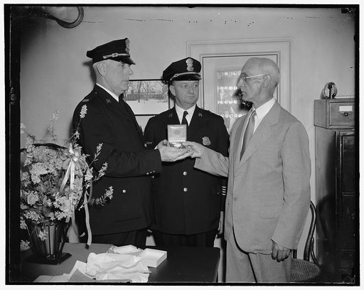 Reward for 22 years service at White House. Washington, D.C., July 6. Retiring after 22 years on the White House Police Force, Captain Alpheus Walter, right, was presented with a watch today from memebers of the force at the White House, the presentation was made by Capt. John D. McCubbin, left; who