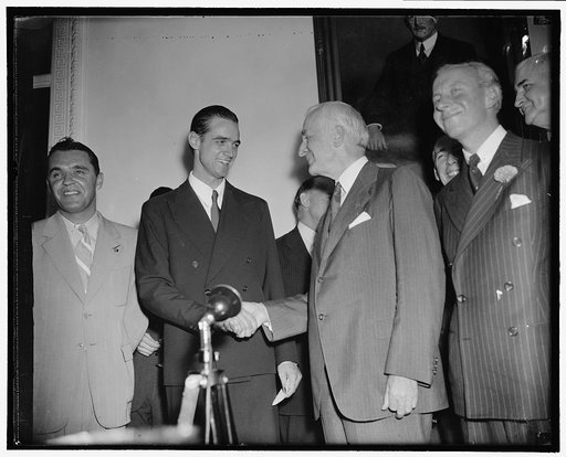 Sec. of State greets Howard Hughes. Washington, D.C., July 21. Secretary of State Cordell Hull, congratulates Howard Hughes on his round the world flight, photographed at the State Dept. today, 7/21/38