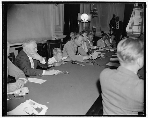 Dies' young son learns of un-American activities first hand. Washington, D.C., Aug. 12. Young Bobby Dies, son of Rep. Martin Dies, Chairman of the Special House Committee investigating un-American activities, listens intently as his father questions witnesses before the committee today. On the left 