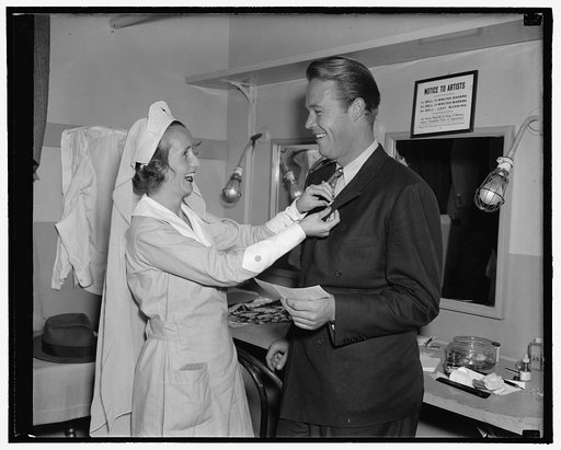 Wayne Morris, motion picture star, is enrolled in the Red Cross by Mrs. Mary Holland, of Bradley Hills, MD. Morris is making a personal appearance at the Earle Theater, 9/28/38