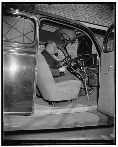 Sergeant Frank M. Beall, in charge of the station, seated in the experimental 2-way communication car. He is removing the telephone transmitter to make a call, 10/38