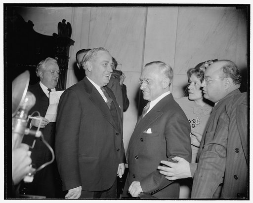 Frankfurter critic passes by. Washington, D.C., Jan. 12. Probably it was just a coincidence that Mrs. Elizabeth Dilling, right, anti- Communist author, was passing by as this picture of Prof. Felix Frankfurter talking to Senator Alexander Wiley of Wisconsin in the Senate Judiciary Subcommittee heari
