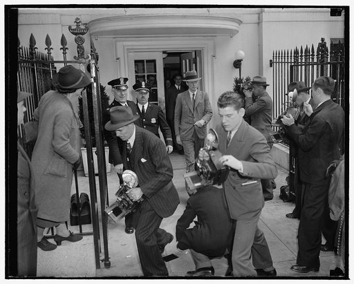 Lindbergh stymied by photographers. Washington, D.C., April 20. Camera-shy Col. Charles A. Lindbergh leaving the White House after a conference with President Roosevelt today, found all exits well 'covered' by news cameramen. Here we see the famous flyer running the photographer's gauntlet as he eme