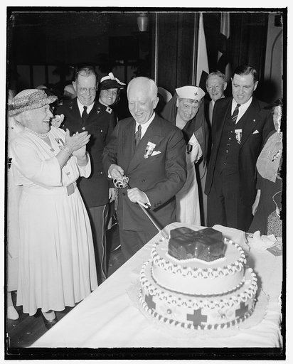 Gray Ladies celebrate twelfth birthday. Washington, D.C., April 26. Norman Davis, Chairman of the American Red Cross, cutting the birthday cake at the graduation exercises of the twelfth training course of the Gray Lady Unit at Walter Reed Hospital. Mrs. Henry R. Rea, honorary Chairman and founder o