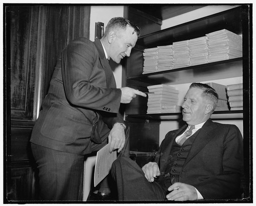 Favor bill to remove tax on gas-alcohol blend. Washington, D.C., May 23. Carl H. Wilkin, Secretary Treasurer of the Raw Materials National Council, and also President of the Progressive Farmers of Iowa is shown talking to William W. Buffum, sitting treasurer and general manager for the Chemical Foun