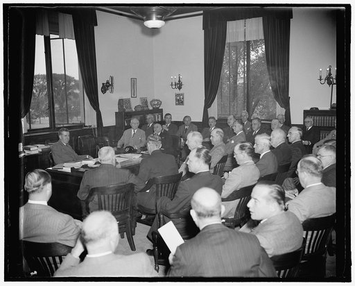Henry A. Wallace at desk facing group