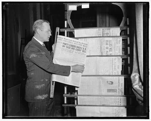 Man displaying front page of Philadelphia Record newspaper from September 21, 1939