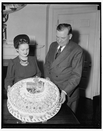 President gets Xmas fruit cake. Washington, D.C., Dec. 19. Brig. Gen. Edwin Watson, a Presidential Secretary, accepting for President Roosevelt a fruit cake from Miss Mildred Cook, Secretary to Rep. A.J. Elliott of California. The cake is a gift from W.C. Baker of Ojai, Calif., who has baked cakes f