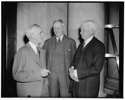 In spotlight at Monopoly Committee hearing. Washington, D.C., Dec. 20. Snapped in an informal conversation at today's session of the National Monopoly Committee were, left to right: Harold Stanley, President of Morgan, Stanley & Co., George Whitney, of J.P. Morgan & Co., and Russell Leffingwell of J
