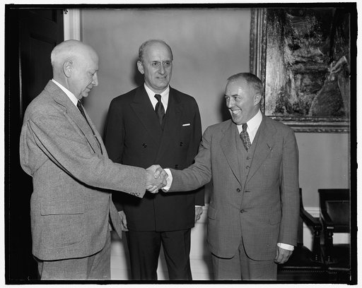 Morgenthau, greets two new additions to the Treasury Department. Washington, D.C., Oct. 1. Preston Delano, left; newly appointed comptroller of the currency, and a distant cousin of the President, greets his assistant, Cyril B. Upham, newly appointed first deputy comptroller of the currency, while t