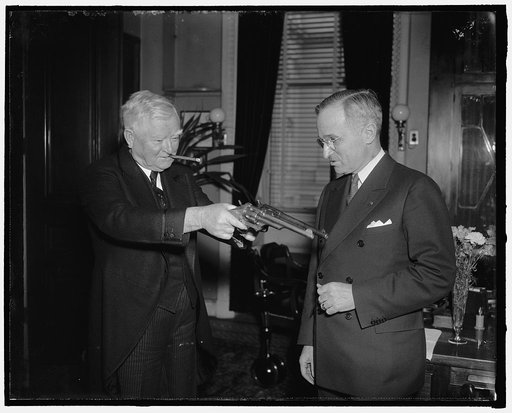 Senatorial stickup. Washington, D.C., Feb. 17. After inspecting a couple of 45-caliber pistols formerly owned by Jesse James, famed bandit of another generation, Vice President Garner playfully tries his "stickup" technique on Senator Harry Truman of Missouri, present owner of the guns. Senator Trum
