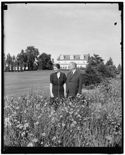 SEC Ickes and bride return home. Olney, Md., June 22. Like a line from the song 'Knee Deep in Daisies and Head Over Heels in Love,' Secretary of Interior Harold Ickes and his bride of a few weeks pictured in the garden of the Ickes country home 'Headwaters' following their return from honeymoon in E