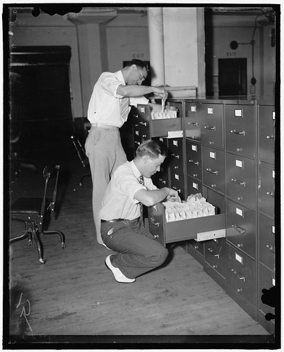 The millions of applications for social security account numbers are handled in orderly manner in the Social Security Board Records Office. After the hour and date, and the number of each application has been recorded, as it is received, applications are sent to 'holding files.' Here they are held u