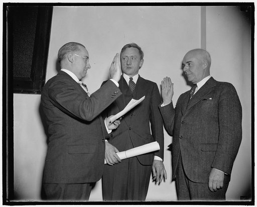 Takes oath as S.E.C. Commissioner. Washington, D.C., Dec. 2. Rep. Edward C. Eicher of Iowa, recently appointed by President Roosevelt to be a member of the Securities and Exchanges Commission, is pictured being administered the oath of office today by Francis P. Brassor, left, Secretary of the Commi