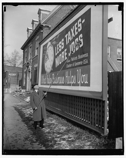 Anti tax poster put up by Chamber president. Washington, D.C., Jan. 18. 'Less taxes, more jobs' reads the poster being pasted up by George H. Davis. It is the first of 25,000 such signs which will be put up all over the nation as part of a drive for reduction in taxes by the U.S. Chamber of Commerce