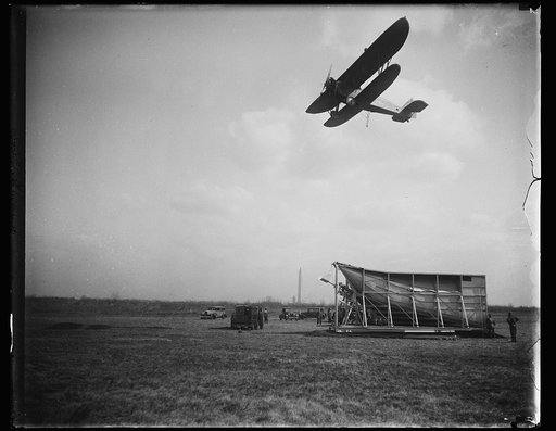 Demonstration of a device invented by Dr. Lytle S. Adams that would allow an airplane to pickup airmail, Hoover Field, Arlington, Virginia; Washington Monument in distance