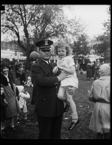 "Lost in action." Little Gloria Largent was the first youngster to stray away from her parents on the White House lawn today where thousands of Washington children rolled their Easter eggs today. White House officer B.B. Bradley is holding Gloria