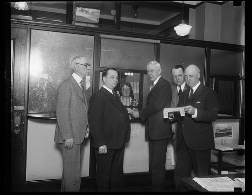 Graf Zeppelin stamps go? Assistant Postmaster General Frederic A. Tilton purchasing the first Graf Zeppelin stamps which were sold at the Washington city post office today. Mrs. M.C. Shaughnessy, Assistant Philatolic Agent, is shown selling the stamps to the General. Others in the photograph, left t
