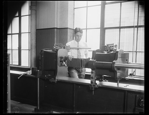 New aviation safety test made. Tests conducted by the Bureau of Standards have indicated than an aviator may exert a pull of approximately 1,000 pounds on his safety belt without breaking it. The photograph shows M.M. Kiley of the Bureau standing beside the machine used in stretching the belts still