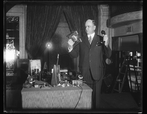 Demonstrates Bell Laboratory wonders. Sergius P. Grace, Vice-President of the Bell Telephone Laboratories, shows the old and the new in telephones. That in his right hand is a model of Alexander Graham Bell's first telephone through which sounds were first electronically transmitted in 1875. The lar