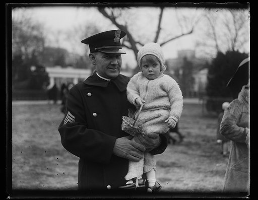 Uniformed man with child holding Easter basket. White House, Washington, D.C.