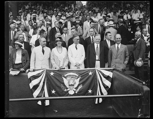 Group in presidential stand; Lou Hoover and Herbert Hoover, front row