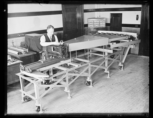 This Isn't a pipe organ. This pipe-organ appearing device in reality is a super-sensitive lens-testing camper [camera?] in the U.S. Bureau of Standards where the government tests products before they are purchased. F.A. Case of the scientific staff is placing a lens in the tester. Dr. I.C. Garnder [