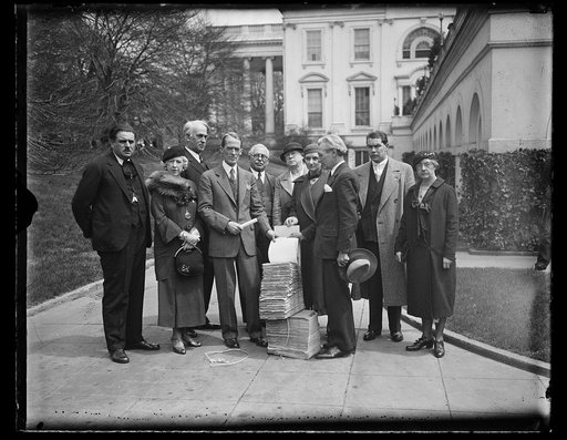 Group at White house with large stack of bound papers