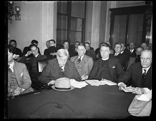 At money hearing. Father Charles Coughlin, radio priest of Mich., listens intently as statesmen and economists give their views on inflation. The picture was made at the monetary conference called by Sen. Elmer Thomas, D. Okla. 1/16/35