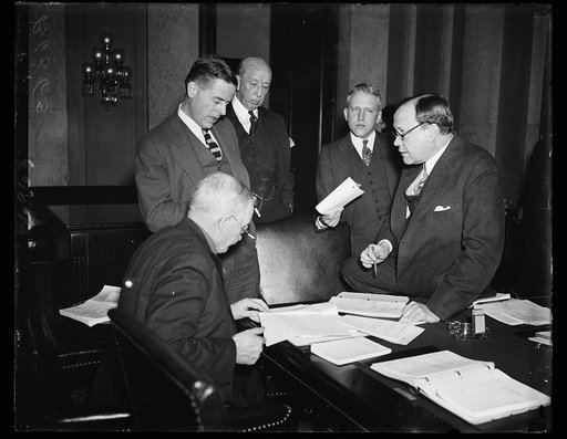 Myers as salesman. FCA Governor W. I. Myers, standing at left, convinces the Senate Banking and Currency Committee that the Farm Credit Bill is all right. He is explaining a point to Sen. Peter Norbeck, R. of S.D., in the chair, while Sen. Robert J. Bulkley, D. of Ohio, with the glasses, listens. 2/