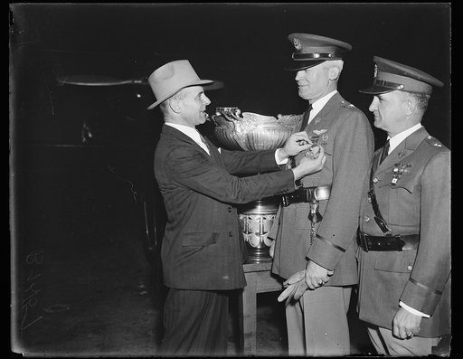 Major James H. Doolittle (left), vice president of the National Aeronautic Association, presents Brigadier Generla Henry H. Arnold with a gold medal to honor his receipt of the Mackay Trophy (in background); Brigadier General Oscar Westover, assistant chief of the Army Air Corps, stands at right