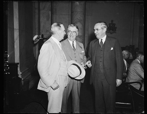 In self-defense. Secretary of Commerce Daniel C. Roper, left, appears at the Senate commerce committee, to defend his department against charges of graft and corruption hurled by Ewing Y. Mitchell, ousted assistant Sen. Royal B. Copeland, D. of N.Y., center , is chairman of the committee, and Sen. A