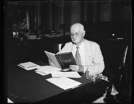 Mischievious. Sen. Duncan C. Fletcher (D. of Fla), Chr. of the Senate Banking Com. looks over a copy of Geo. B. Roberson's "Monetary Mischief" at the Thursday com. meet on Capitol Hill. 7/18/35