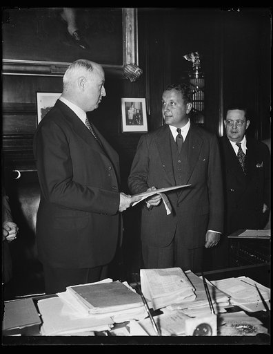 Two dollars a mile on China airmail. PMG James A. Farley, left, receives a bid from Warren Juan Trippe, President of Pan American Airways, for $2 a mile for an 800 pound loan of mail from San Francisco to China. The route is via Honolulu and Manila covering 16,000 miles. 10/21/35