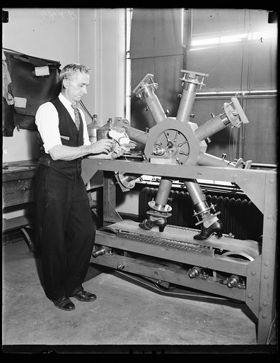 Shoe tester. E.L. Wallace, acting Chief of the Leather Section of the Bureau of Standards, shown with the endurance shoe tester. The tester holds eight shoes to test walking, steps, and sole construction. 10/24/35