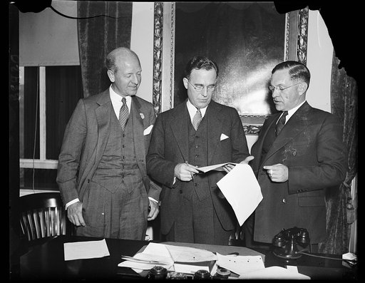 Working on housing display. These representatives of the Manufacturers' Housing Display Council and the Treasury Department discuss methods of stimulating building to care for a shortage of houses indicated in a recent survey. From the left: Peter Grimm, assistant to the Secretary of the Treasury; R