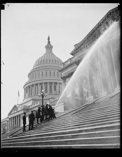 Saturday nigh for Capitol. Captain H.C. Corder, chief of the Washington Fire Department, giving the Capitol its annual bath. The Senate side of the Capitol is shown in the picture getting sprayed by the powerful hoses which take more than two men to hold