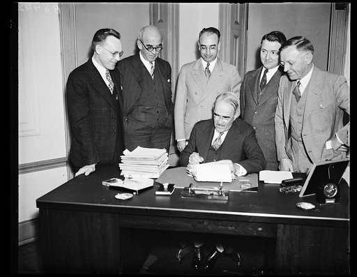 Rural electrification program speeded. Executives of the Rural Electrification Administration gather around their chief, Morris L. Cooke, as seven projects are launched to give 4,000 farm homes electric light. Cooke is seated. From the left, standing: Melvin O. Swanson, Chief Engineer; W.E. Herring,